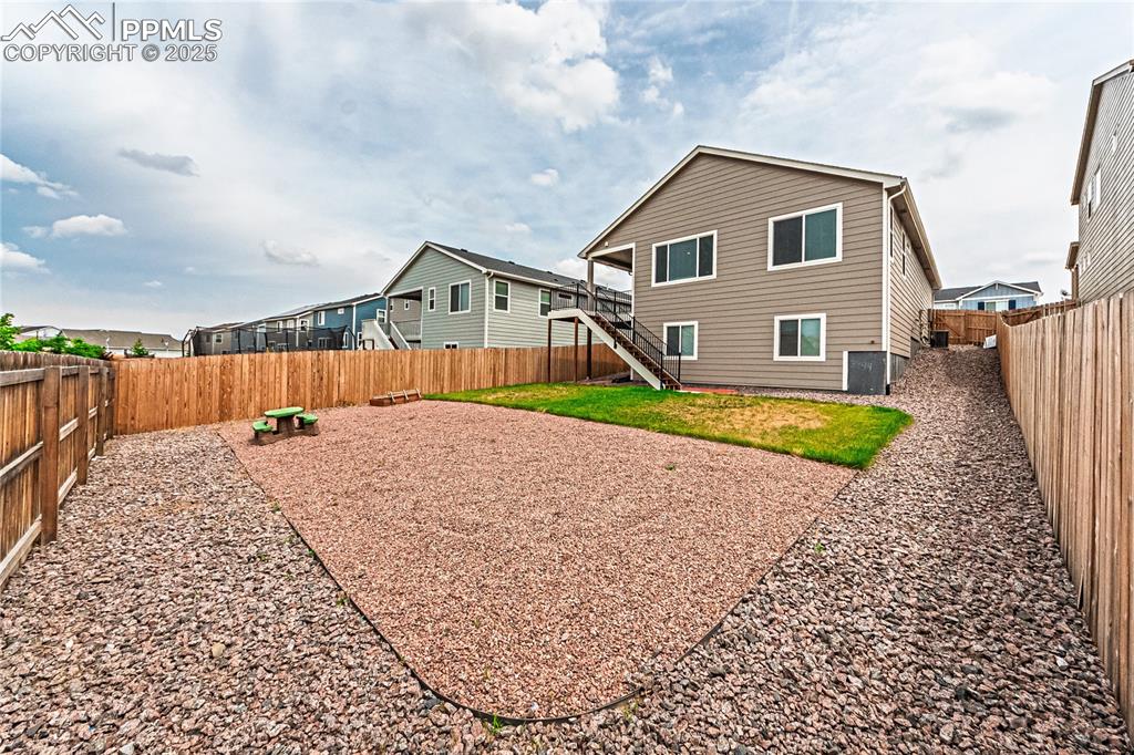 Image 35 of 39: Back of property featuring a fenced backyard, stairway, and a residential v