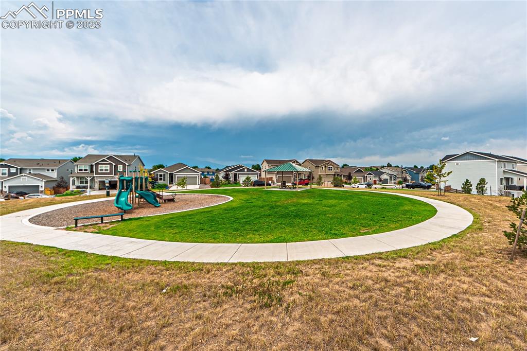 Image 38 of 39: Community jungle gym with a residential view and a yard