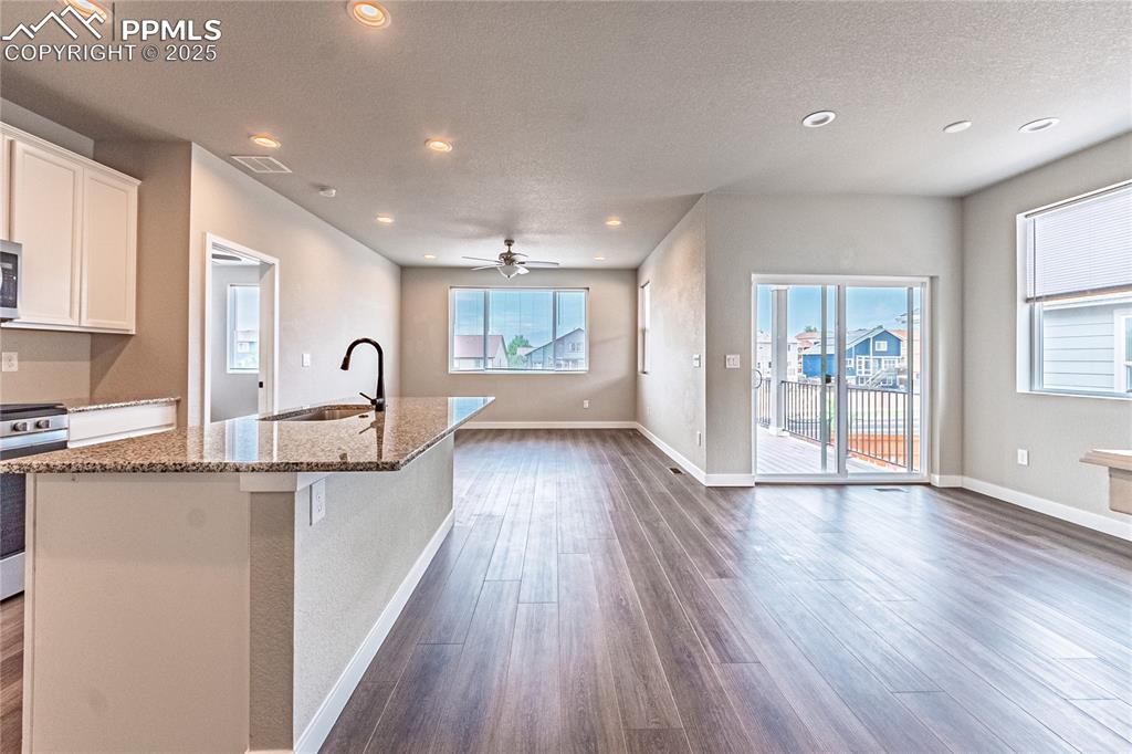 Image 6 of 39: Kitchen featuring dark wood-type flooring, white cabinets, stone counters,