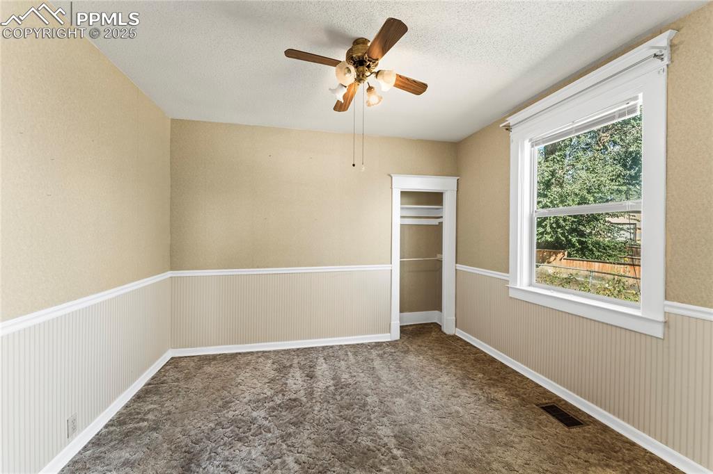 Image 11 of 27: Unfurnished bedroom with a closet, dark colored carpet, a wainscoted wall,