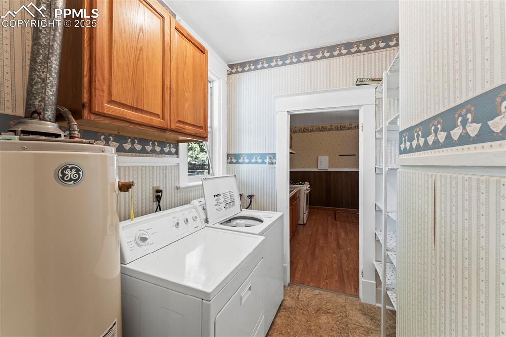 Image 20 of 27: Laundry room featuring water heater, wallpapered walls, washer and dryer, a