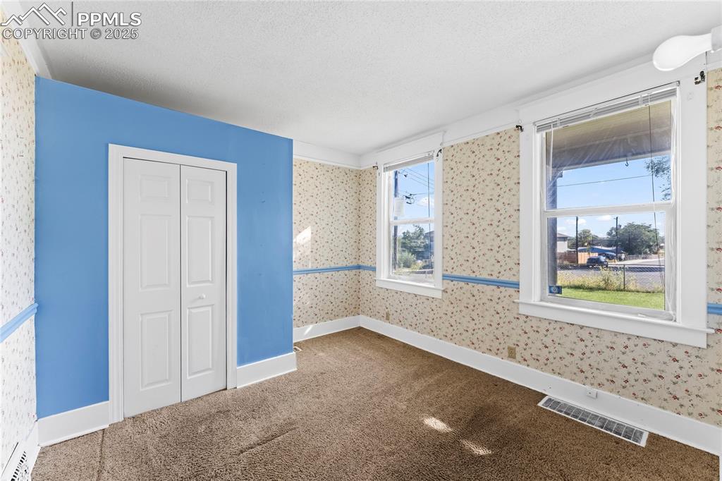 Image 6 of 27: Unfurnished bedroom with carpet flooring, wallpapered walls, and a textured