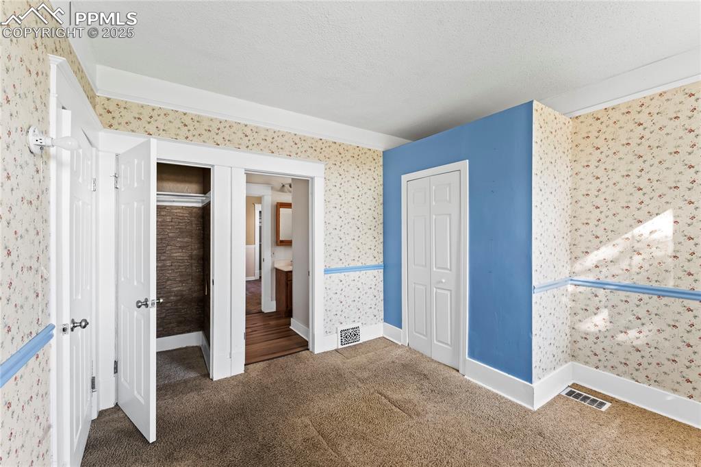 Image 8 of 27: Unfurnished bedroom featuring wallpapered walls, carpet floors, a closet, a