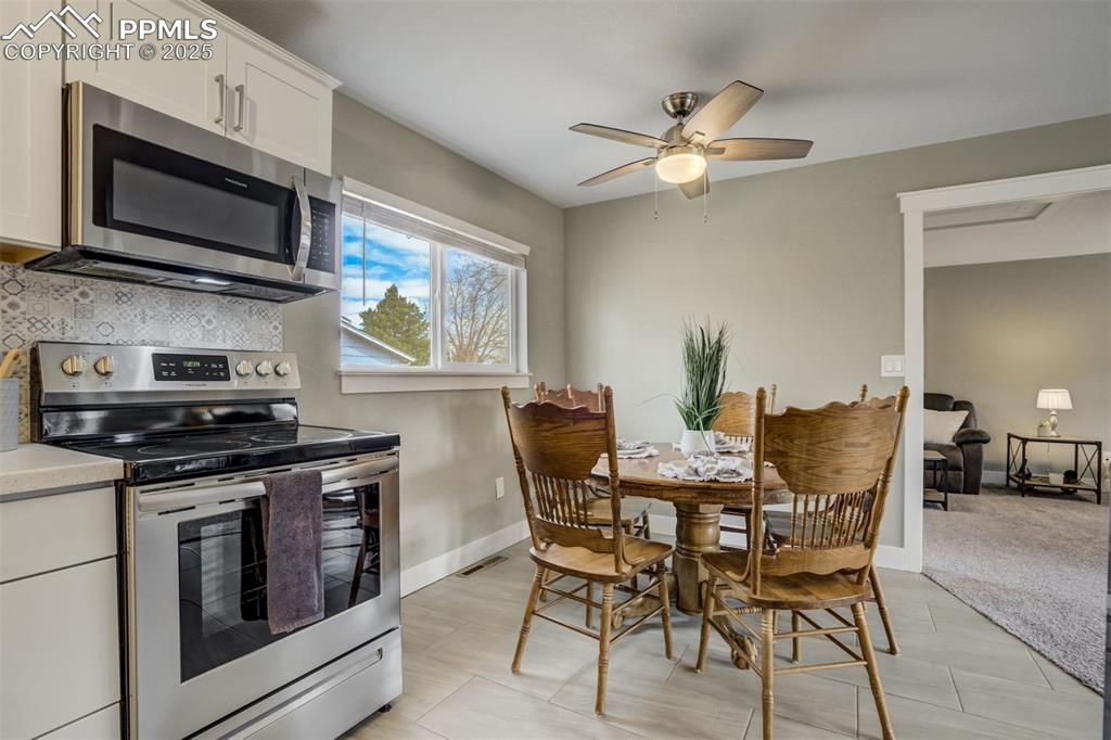 Image 11 of 29: Kitchen with stainless steel appliances, white cabinets, backsplash, and ce