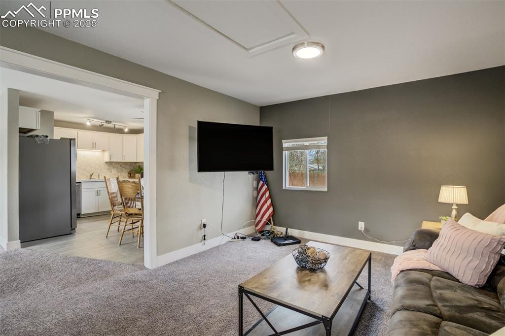 Image 13 of 29: Living room with light carpet and baseboards
