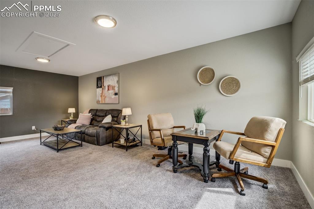Image 15 of 29: Carpeted living area with baseboards and attic access