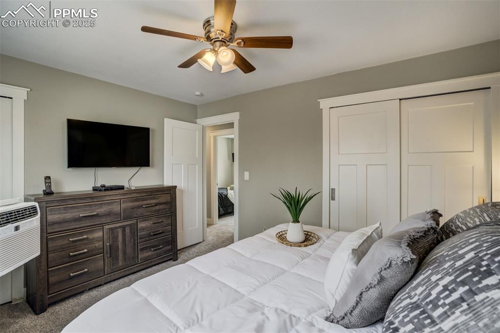 Image 17 of 29: Bedroom with carpet floors, a ceiling fan, a wall mounted air conditioner,