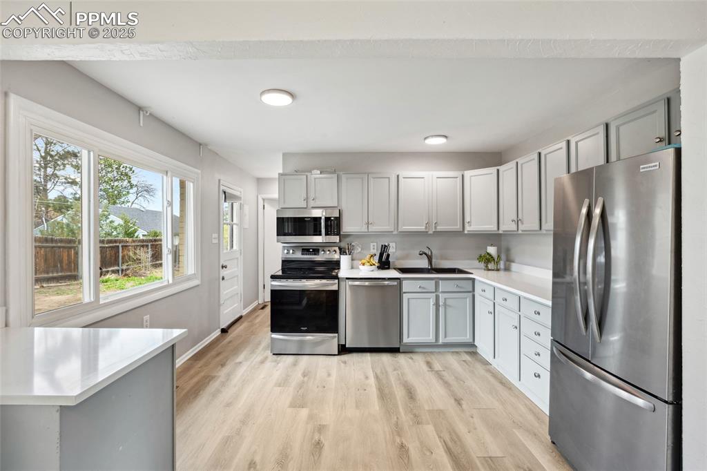 Image 10 of 39: Kitchen featuring a sink, stainless steel appliances, light wood-style floo