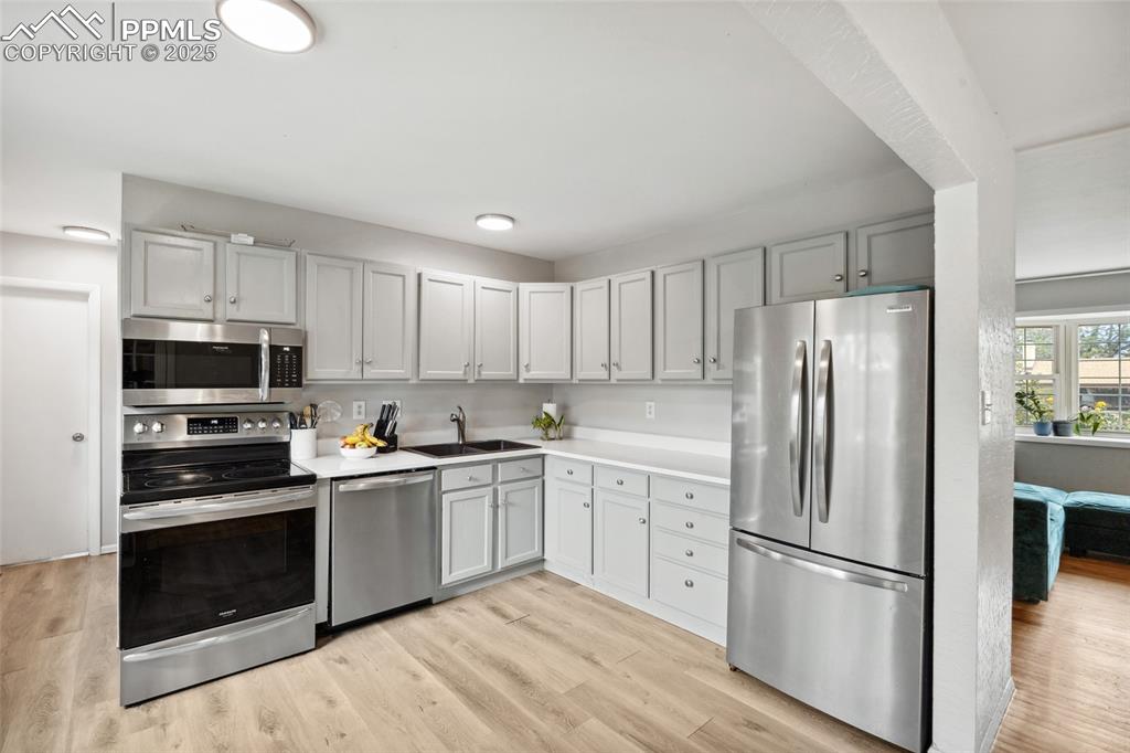 Image 11 of 39: Kitchen featuring appliances with stainless steel finishes, light wood-styl