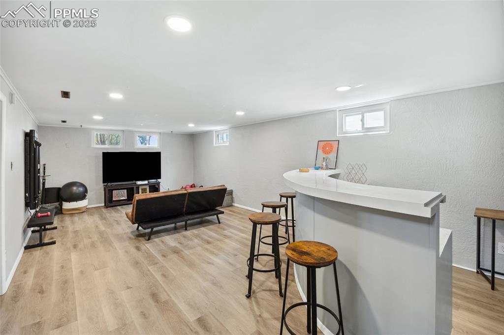 Image 23 of 39: Bar with baseboards, recessed lighting, light wood-type flooring, and crown