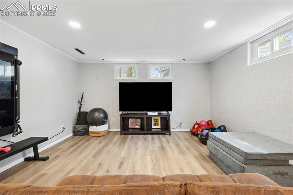 Image 24 of 39: Living room featuring crown molding, recessed lighting, wood finished floor