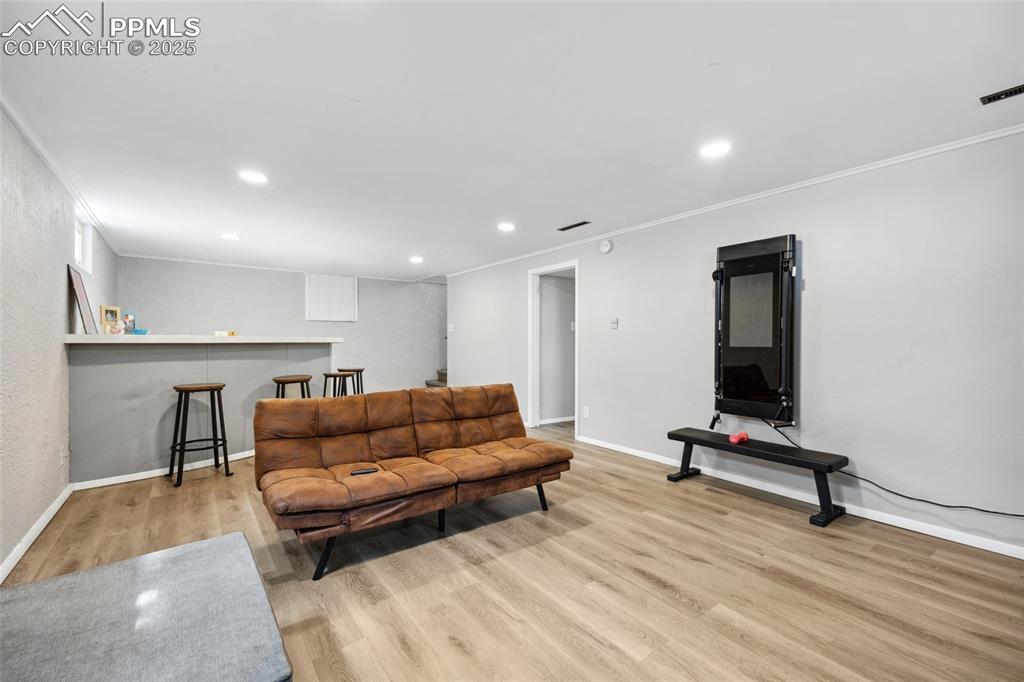 Image 25 of 39: Living room with ornamental molding, recessed lighting, wood finished floor