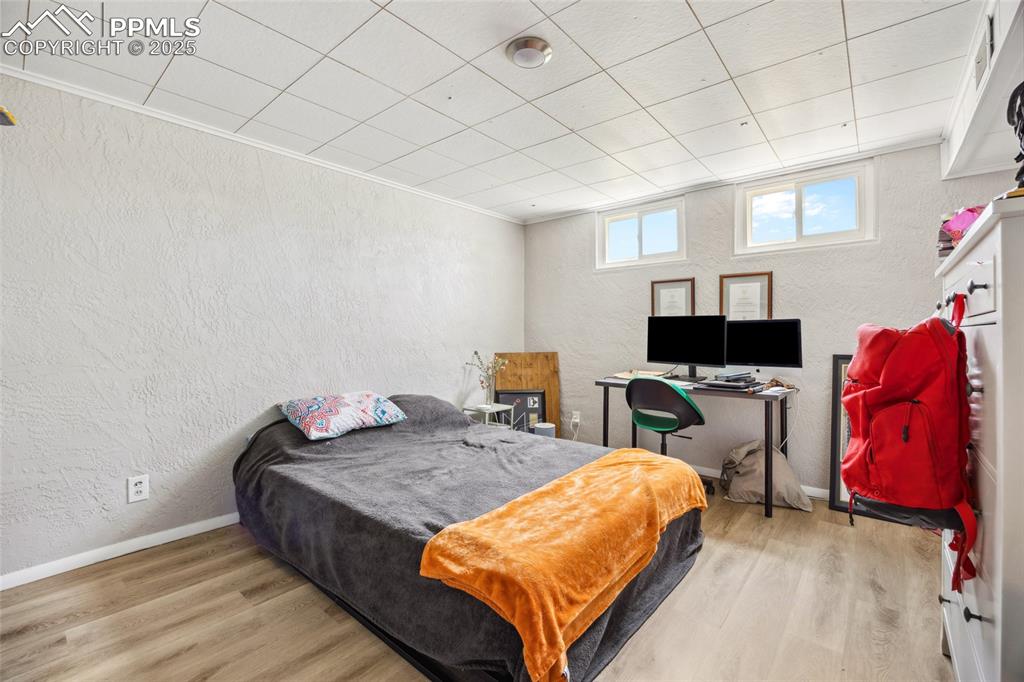 Image 26 of 39: Bedroom featuring a textured wall, wood finished floors, and baseboards