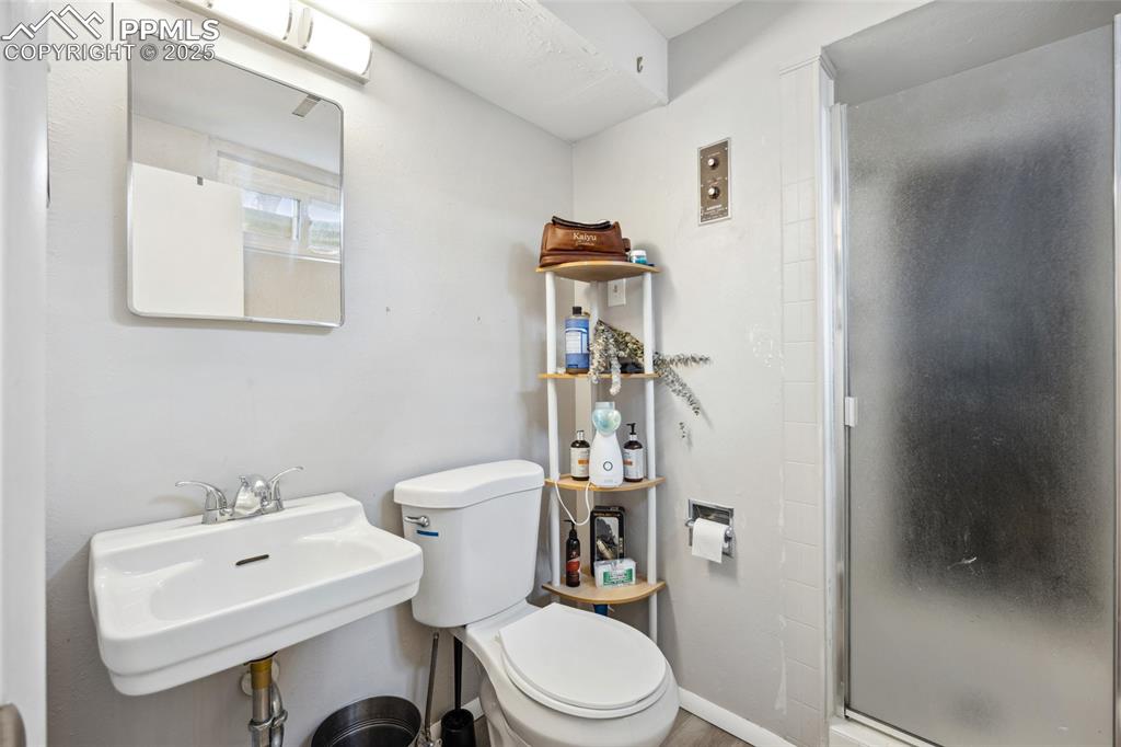 Image 28 of 39: Bathroom with toilet, a stall shower, and a sink