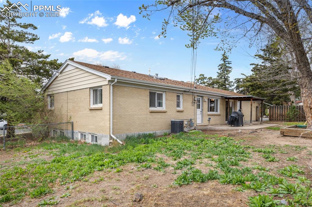 Image 33 of 39: Back of house with fence, central AC, a patio, and brick siding