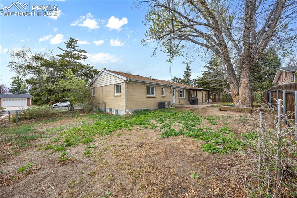 Image 34 of 39: Back of house featuring central AC, a patio, brick siding, and a fenced bac
