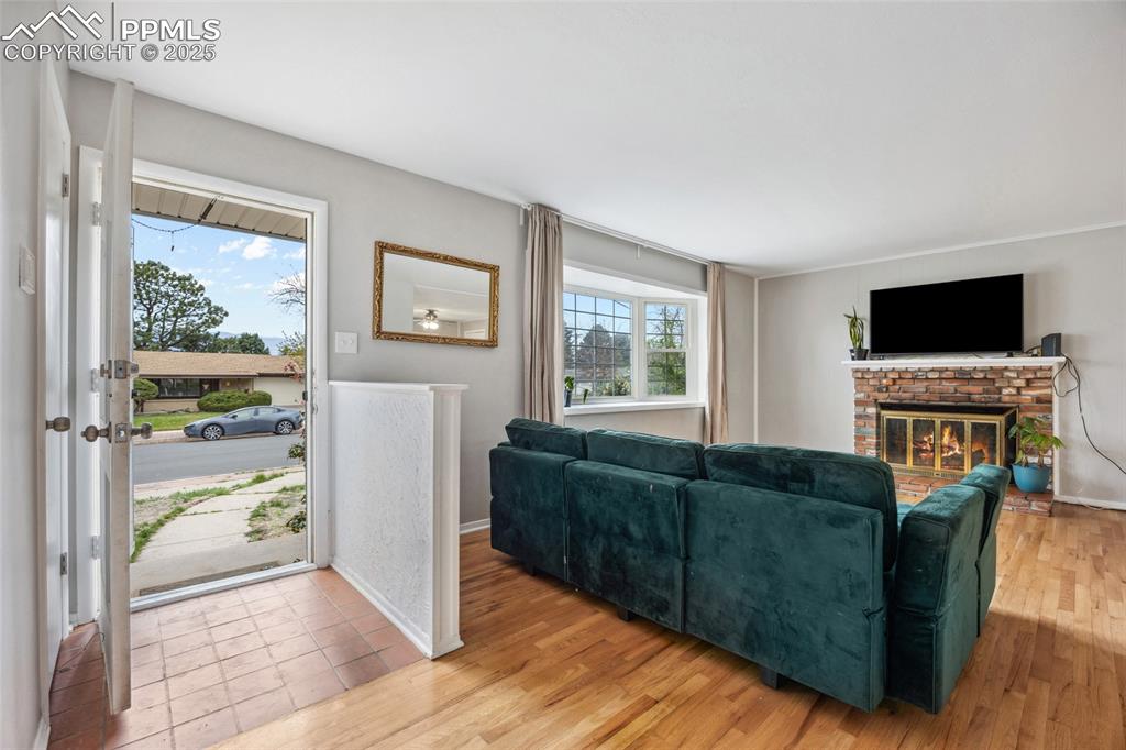 Image 4 of 39: Living area featuring baseboards, light wood-style flooring, and a brick fi