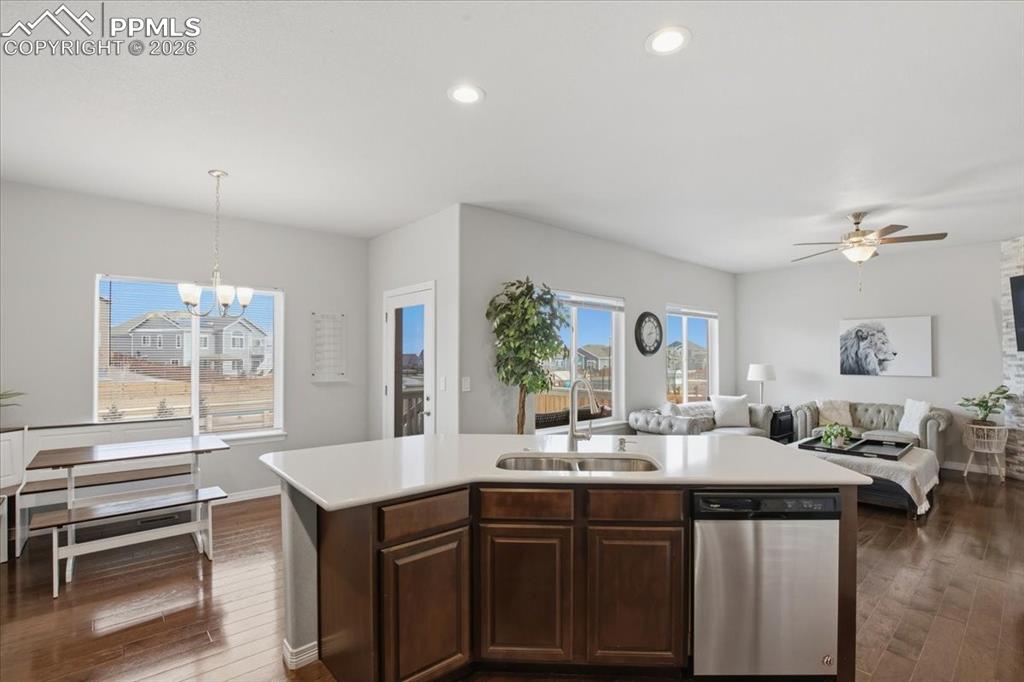 Image 12 of 40: Kitchen with light countertops, dishwasher, dark wood-type flooring, hangin