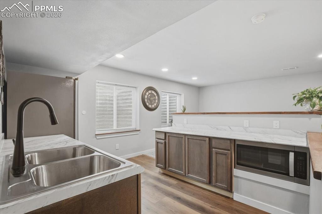 Image 33 of 40: Kitchen with stainless steel microwave, light wood-type flooring, dark brow