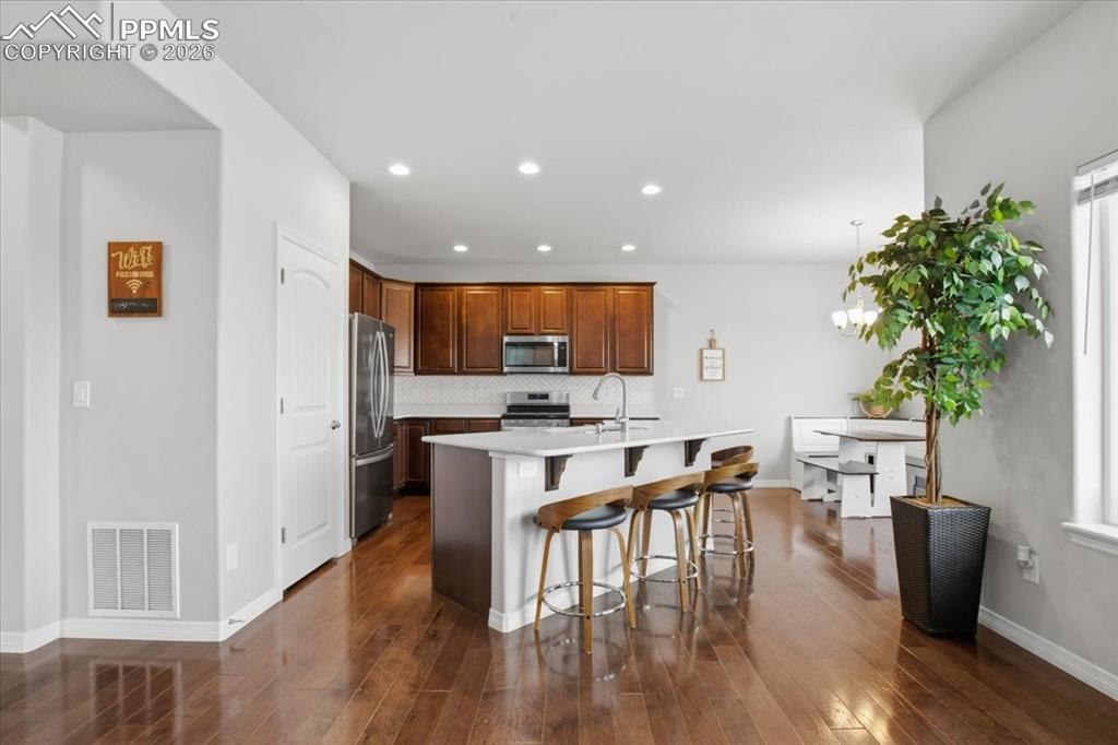 Image 9 of 40: Kitchen with a breakfast bar area, backsplash, stainless steel appliances, 