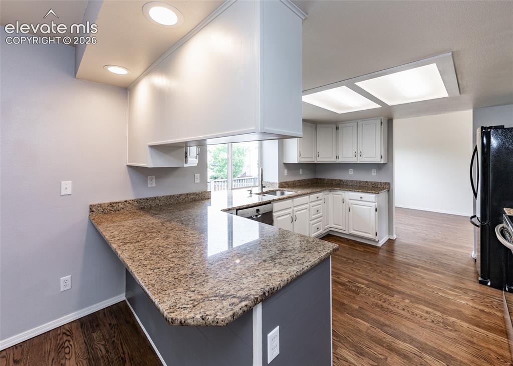 Image 17 of 41: Kitchen featuring wood-finish flooring, recessed lighting, and white cabine