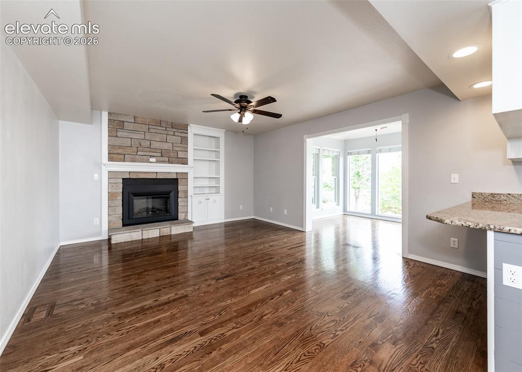 Image 18 of 41: Living area featuring wood-finish flooring, a stone-faced fireplace with a 