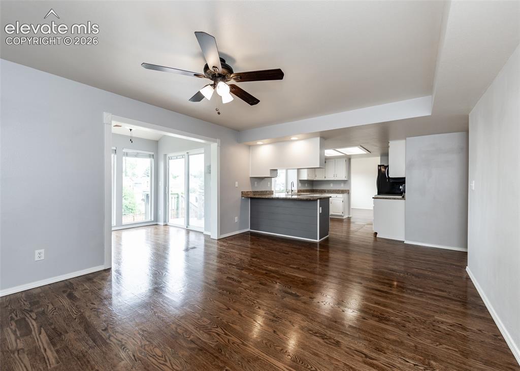 Image 19 of 41: Spacious living area featuring rich wood-finish flooring, a ceiling fan, an