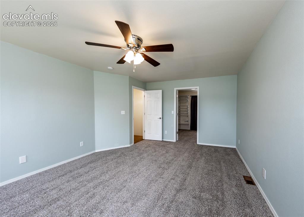 Image 24 of 41: Spacious room featuring light blue walls, gray carpet, a ceiling fan with i