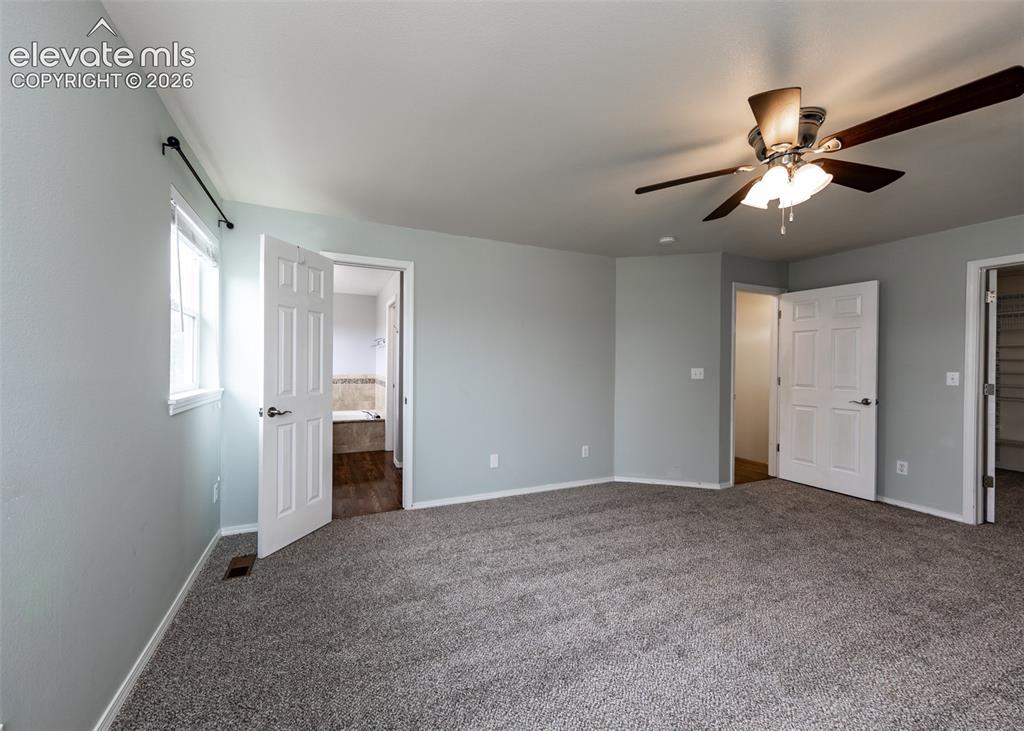 Image 25 of 41: Spacious room featuring light gray walls, carpet flooring, and a ceiling fa