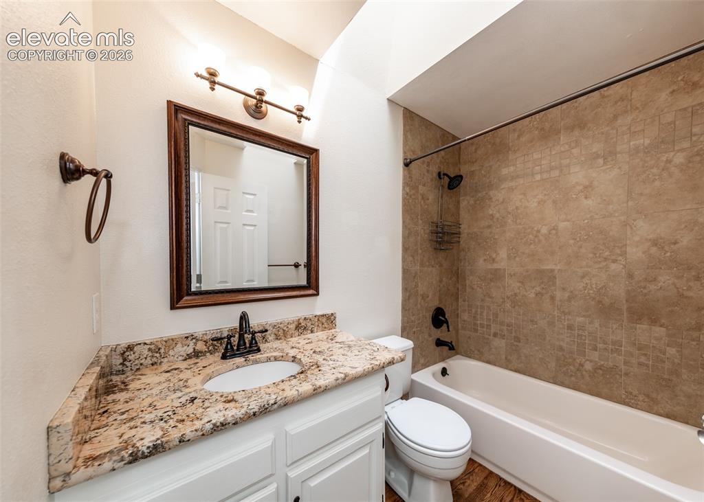 Image 29 of 41: Bathroom featuring a white vanity with a natural stone countertop, undermou