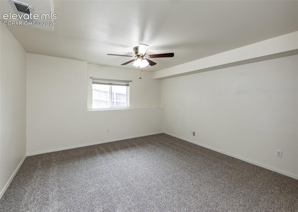 Image 32 of 41: Spacious room featuring gray speckled carpeting, neutral wall paint, and a 