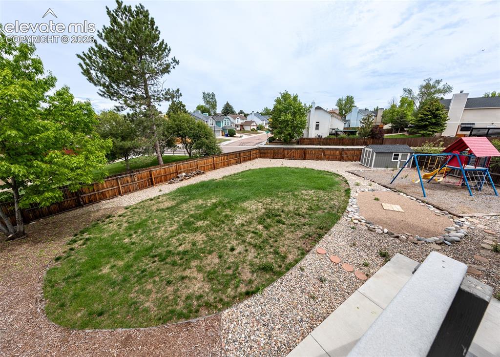 Image 36 of 41: Expansive fenced backyard featuring a generous lawn area, gravel pathways, 