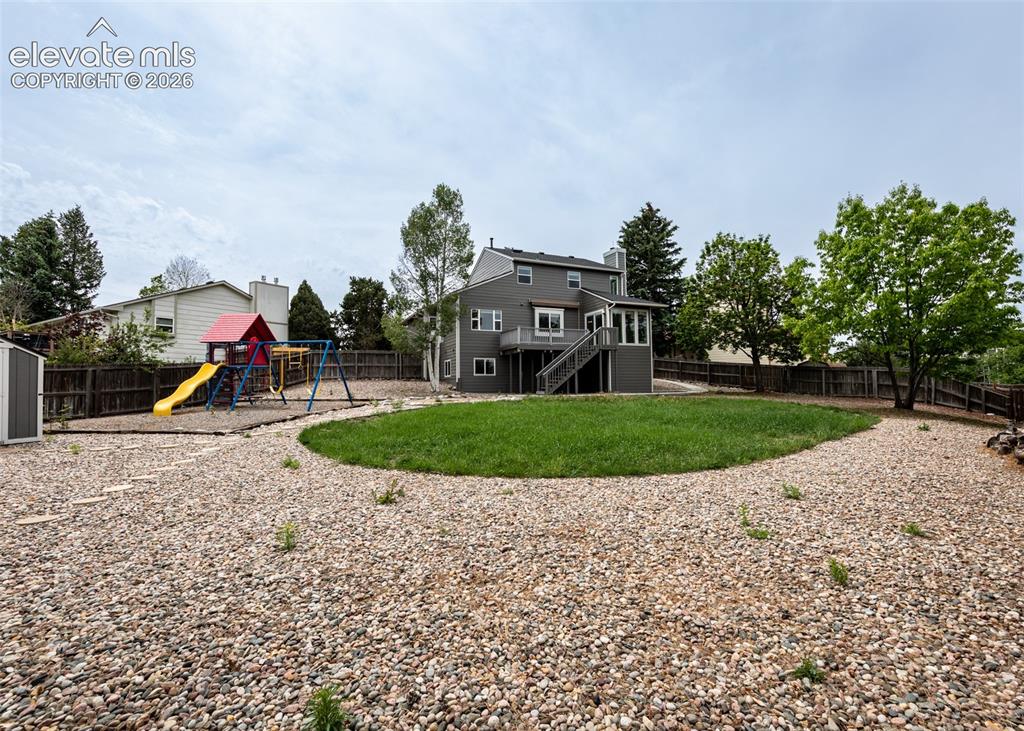 Image 38 of 41: Spacious backyard featuring a central lawn area, extensive gravel landscapi