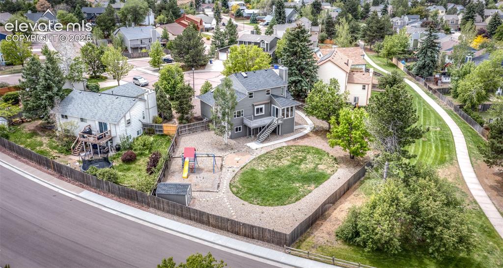 Image 7 of 41: Fenced backyard featuring a gravel patio, green lawn area, and mature trees