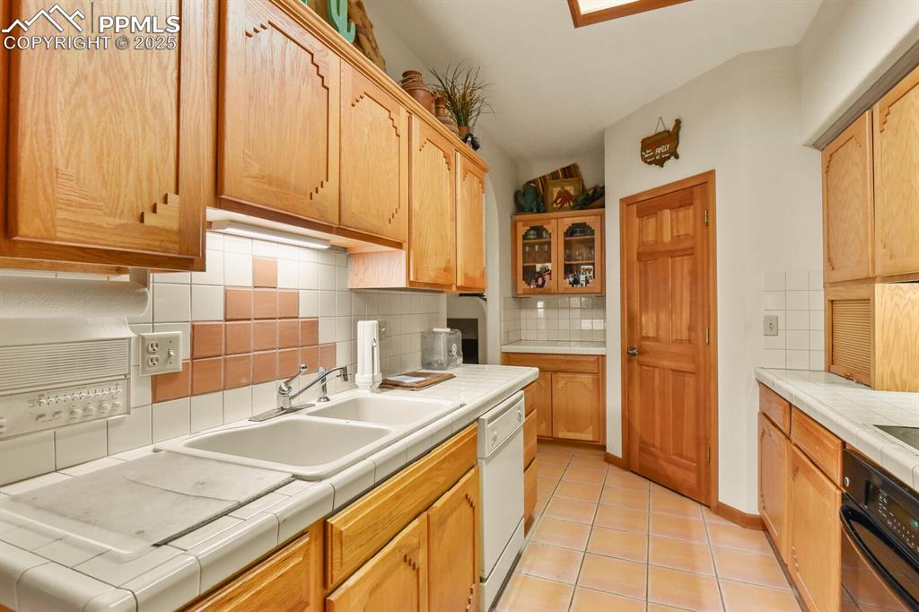 Image 10 of 48: Kitchen with tasteful backsplash, tile countertops, oven, light tile patter