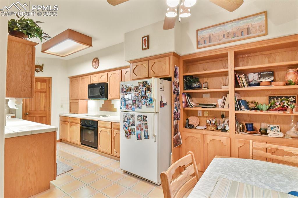 Image 13 of 48: Kitchen featuring black appliances, tile countertops, light tile patterned