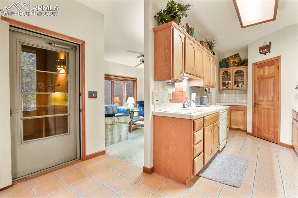 Image 14 of 48: Kitchen with tasteful backsplash, light tile patterned floors, tile counter