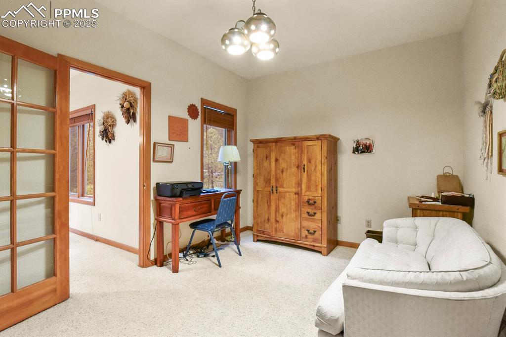 Image 16 of 48: Home office with light carpet and a chandelier