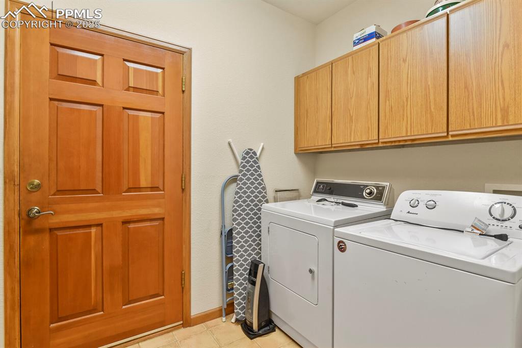 Image 24 of 48: Laundry room with washer and dryer, light tile patterned flooring, and cabi