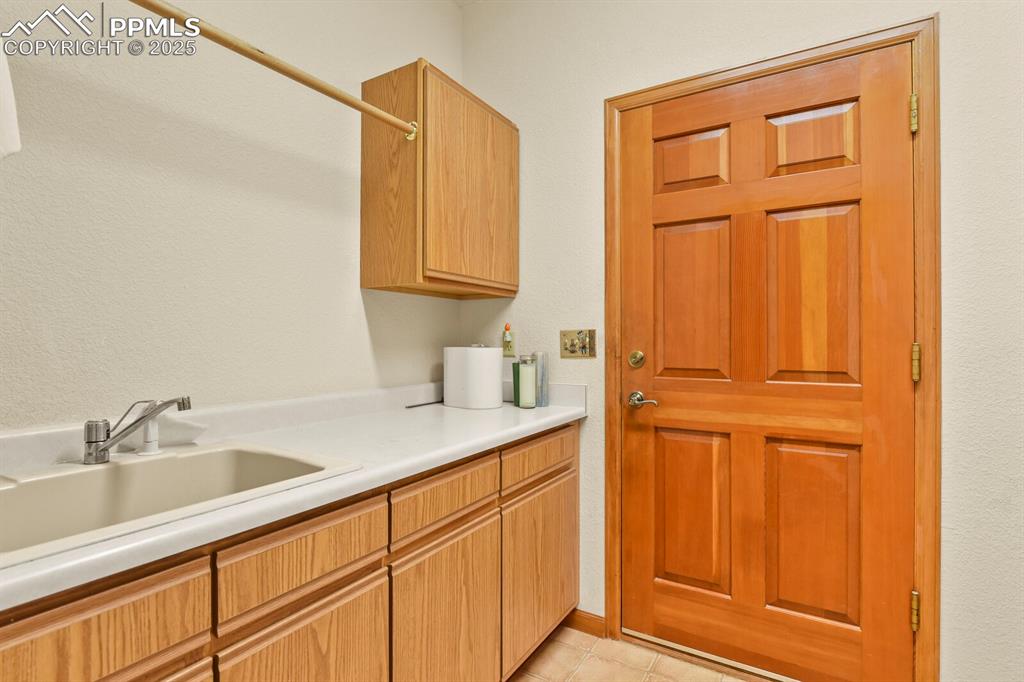Image 25 of 48: Laundry room featuring a textured wall and light tile patterned floors