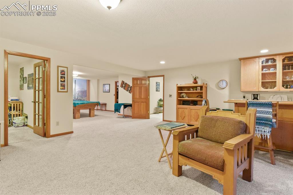 Image 27 of 48: Living area with light carpet, pool table, and recessed lighting