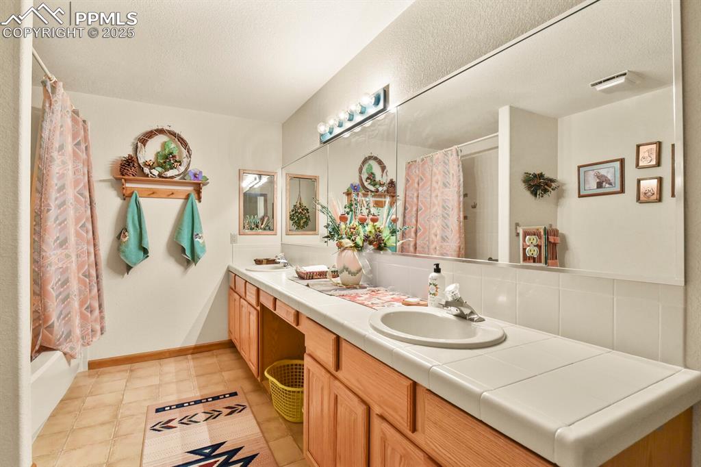 Image 33 of 48: Full bathroom featuring double vanity, shower / bathtub combination with cu