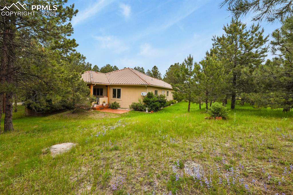 Image 38 of 48: Rear view of property featuring a tiled roof, stucco siding, and a patio
