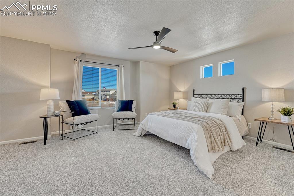 Image 15 of 29: Primary suite with carpet, ceiling fan...