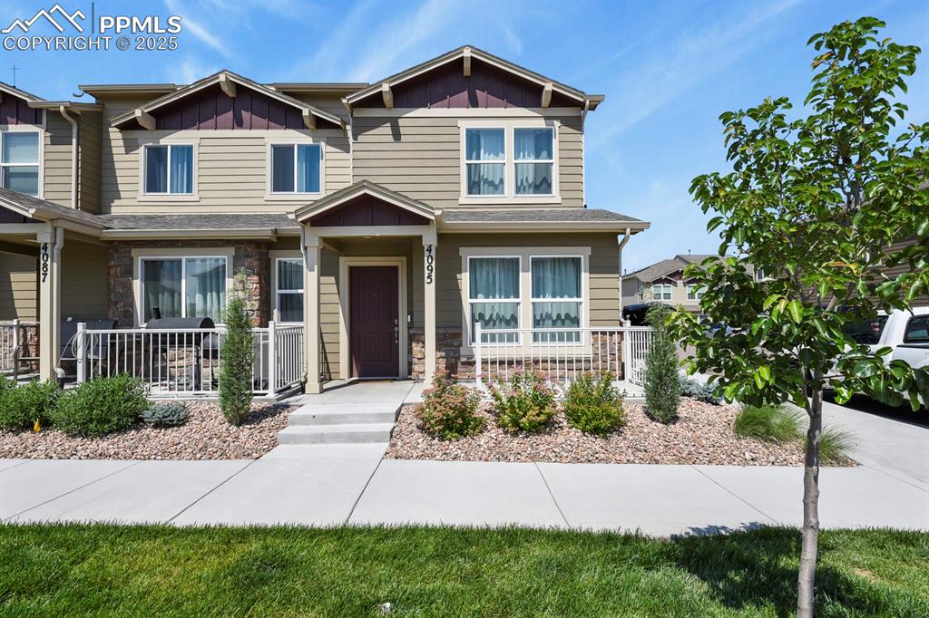 Caption: View of front facade featuring a porch, stone siding, and board and batten siding