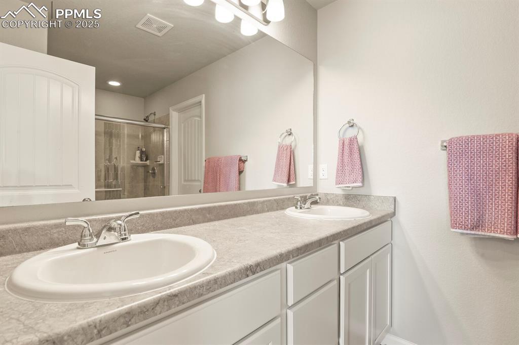 Image 21 of 27: Bathroom with double vanity and a stall shower