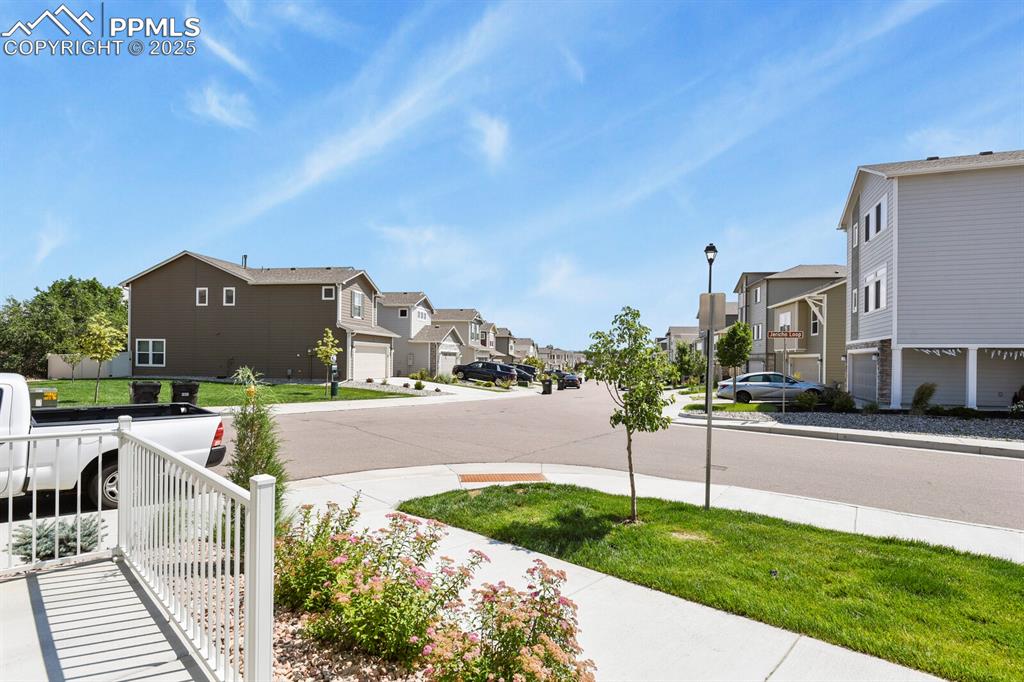 Image 23 of 27: View of asphalt street with a residential view, street lights, and sidewalk