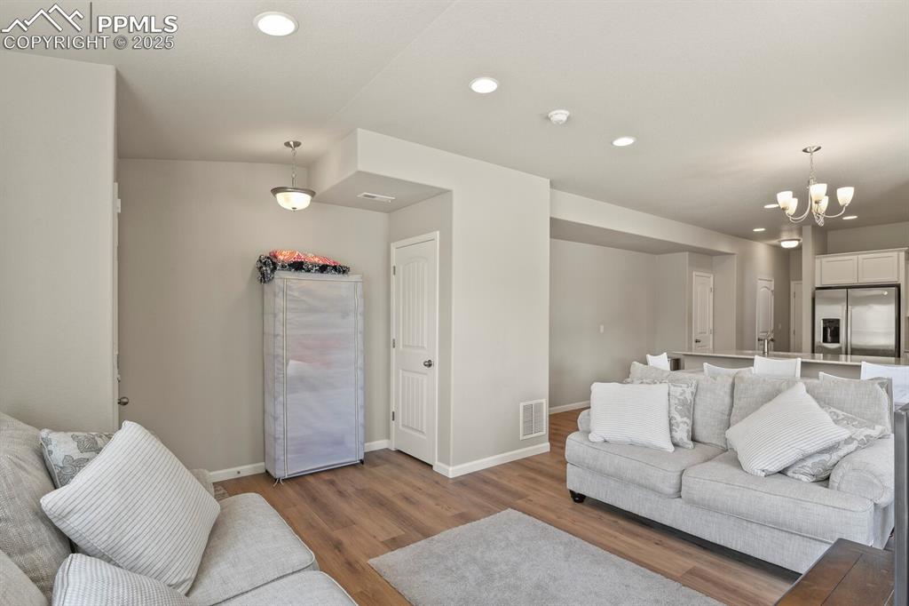 Image 3 of 27: Living area featuring wood finished floors, a chandelier, and recessed ligh