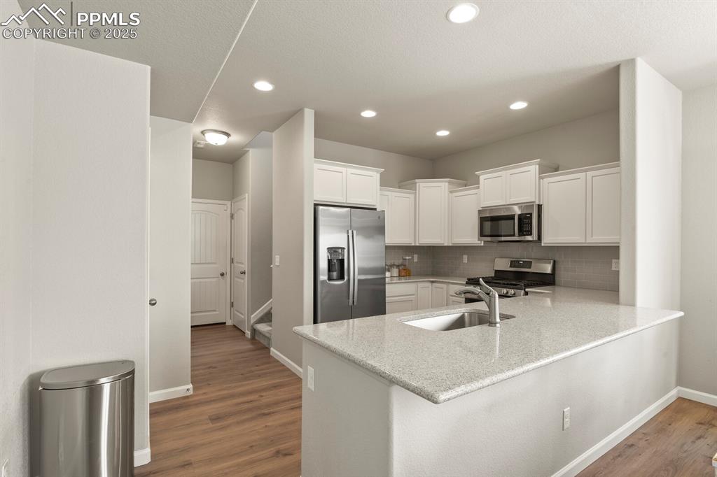 Image 8 of 27: Kitchen with stainless steel appliances, a peninsula, wood finished floors,