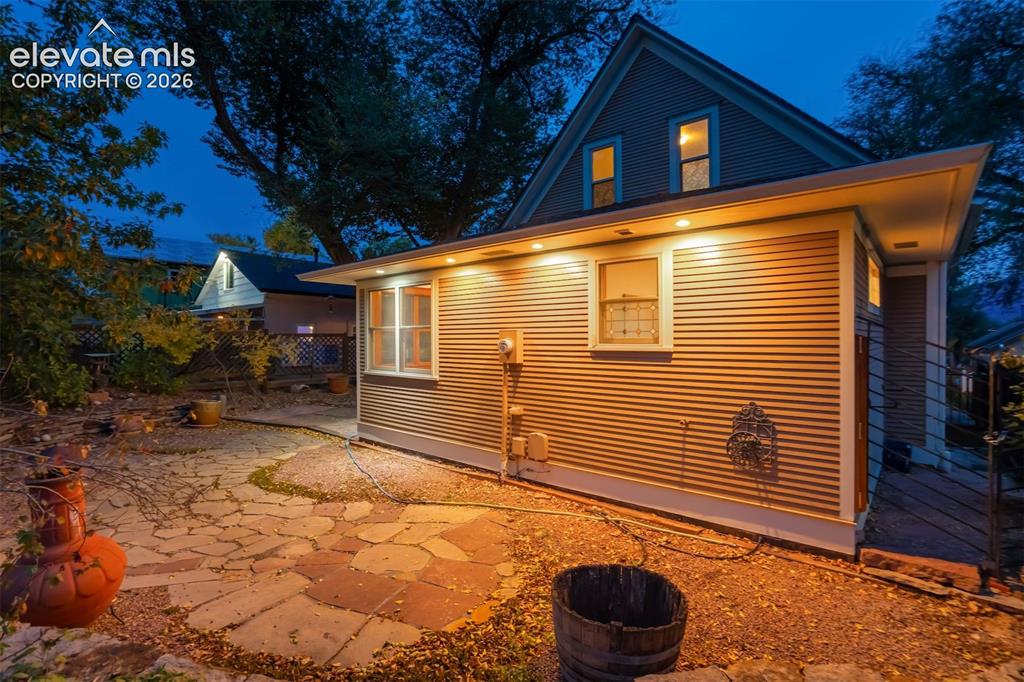 Image 29 of 40: Flagstone patio with exterior lighting and ribbed siding